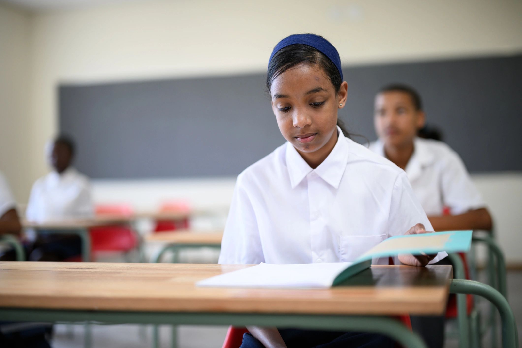 Student opening a schoolbook in class